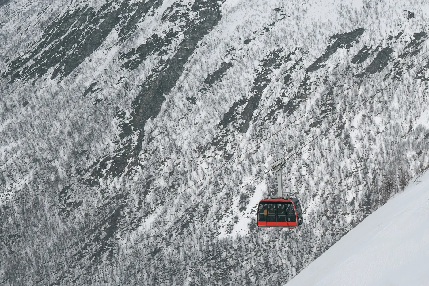 A red cable car cabin above a snow-covered slope