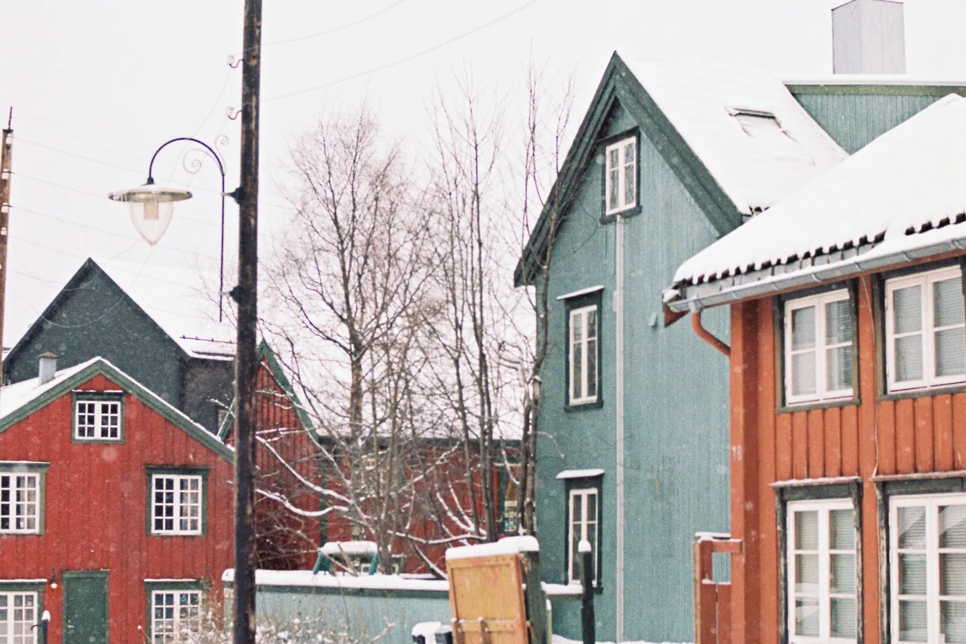 Colourful wooden houses and a street lamp in the snow in Tromsø