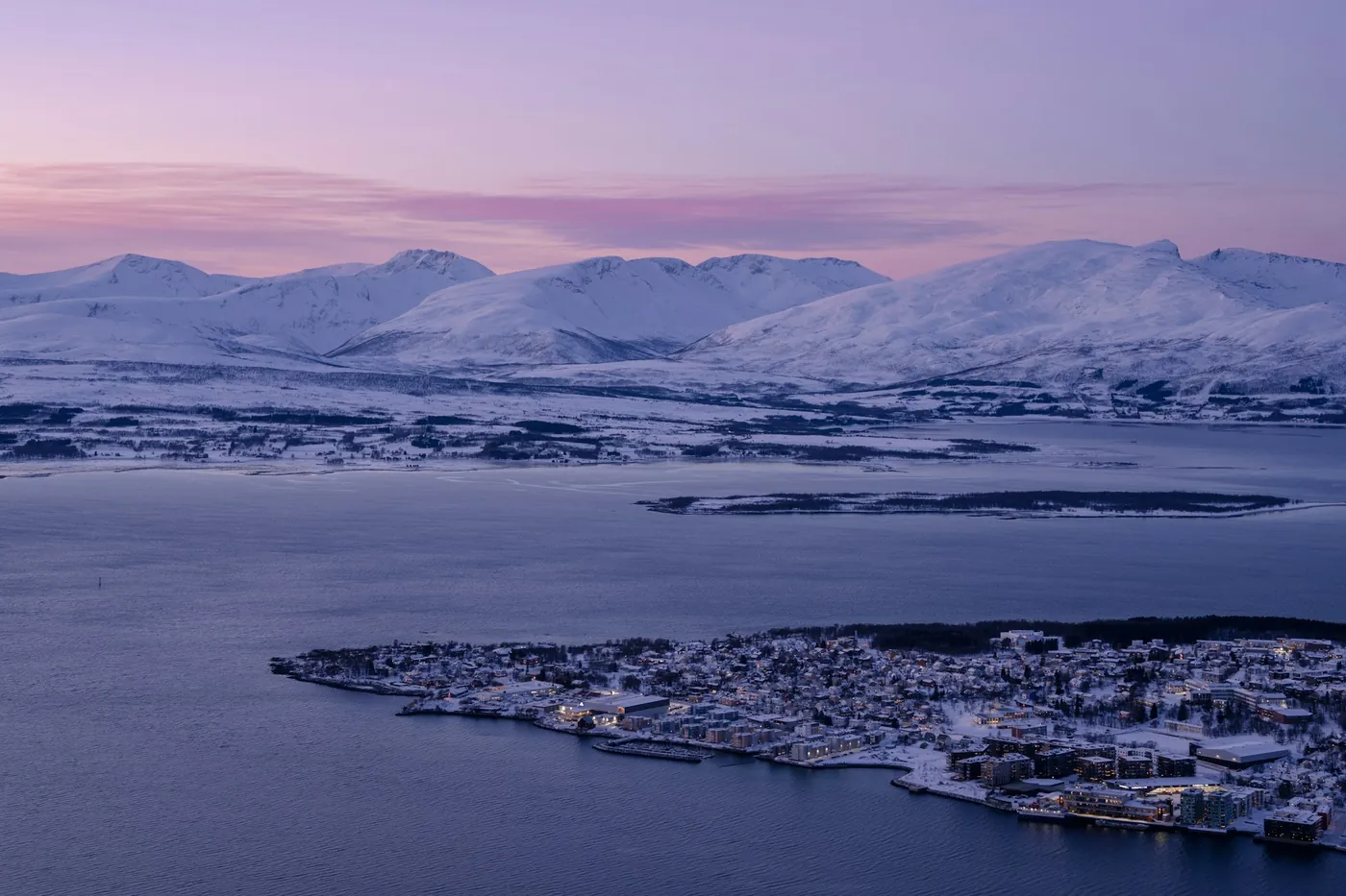 Città su un'isola sotto un cielo viola con montagne innevate sullo sfondo