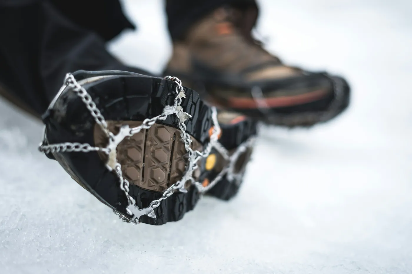 Shoe with ice spikes pulled over the sole, standing in snow