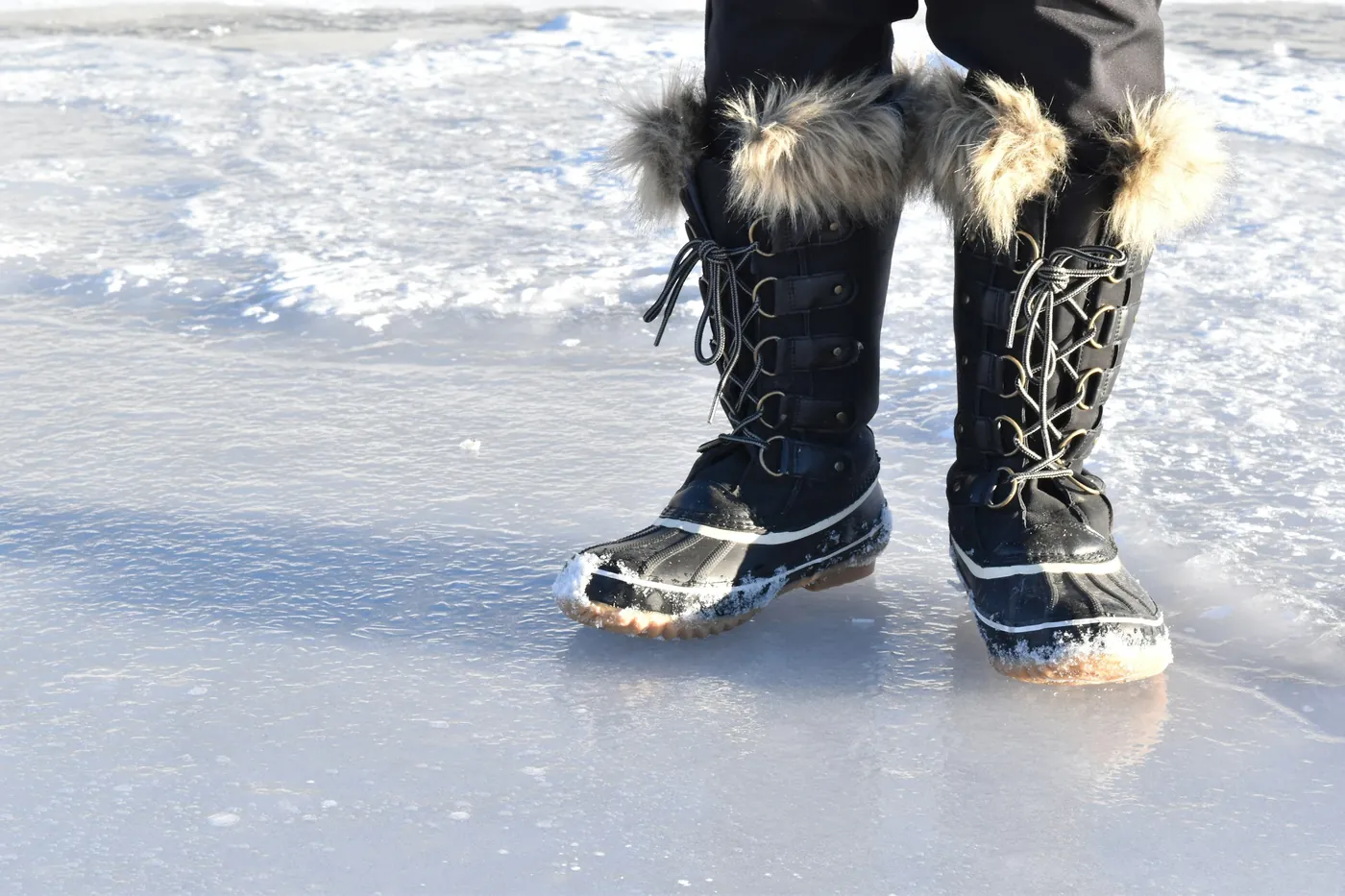 Fur-lined winter boots standing on ice